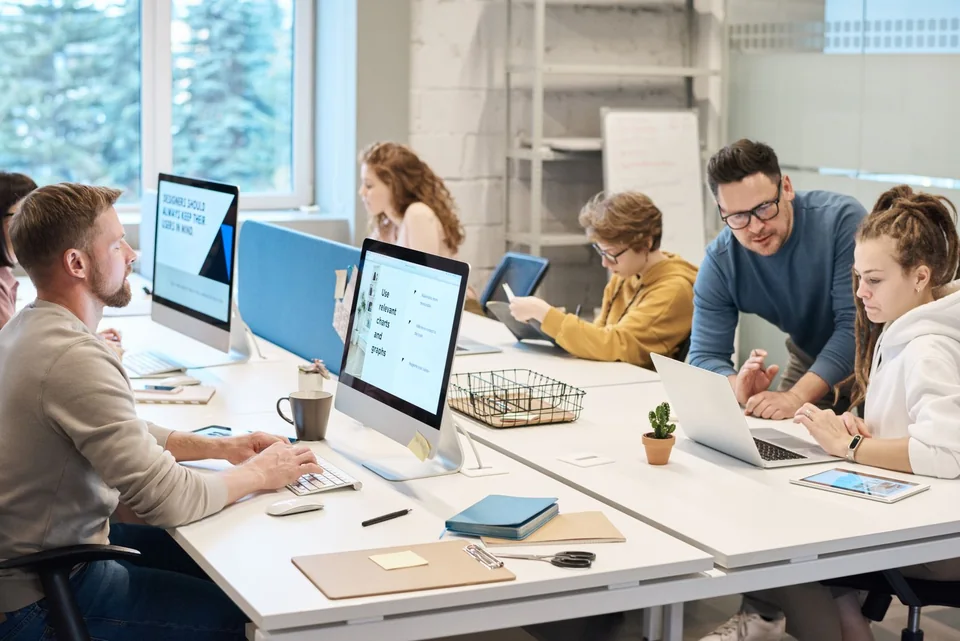 A team working together with desktop computers, laptops and a tablet.