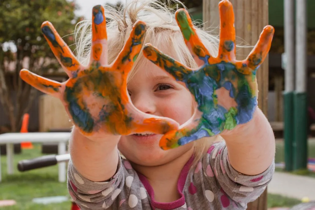 A child showing her paint-covered hands.